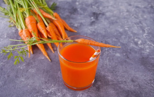 Karottensaft im Glas auf konkretem Hintergrund