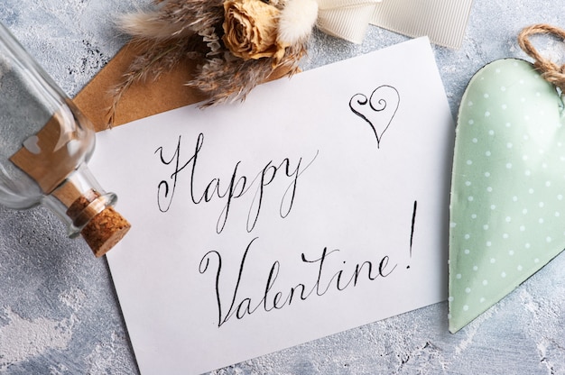 Karte mit Happy Valentine Kalligraphie und Kraftumschlag mit grünem dekorativem Herzen