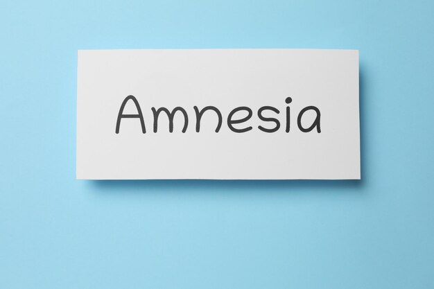Karte mit Wort Amnesie auf Draufsicht des hellblauen Hintergrundes