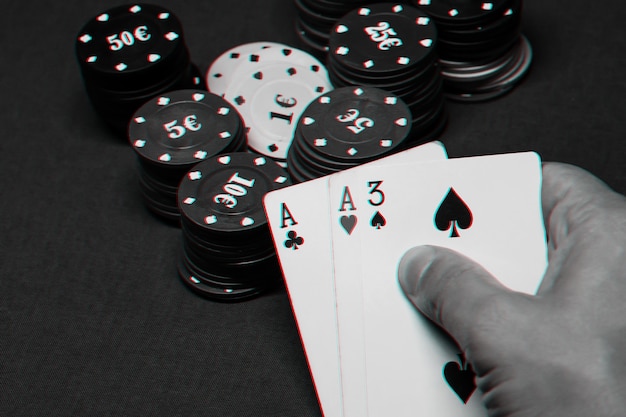 Karten mit einem Paar Asse in den Händen eines Pokerspielers in einem Casino auf dem Tisch mit Chips. Schwarzweißfoto mit Glitch-Effekt