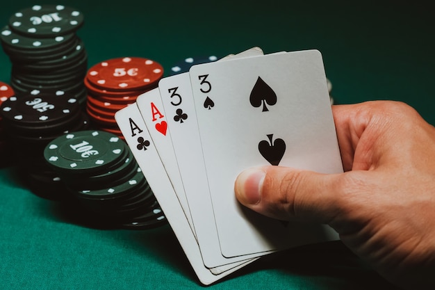 Karten mit zwei Pokerpaaren in den Händen eines Spielers auf dem Hintergrund von Spielchips