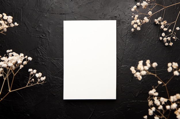Kartenmodell, leere Hochzeitseinladung mit weißem Blumendekor auf schwarzem Hintergrund. Grußkarte