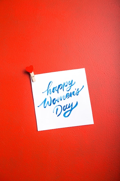 Kartennachricht mit glücklichem Frauentag auf rotem Tisch