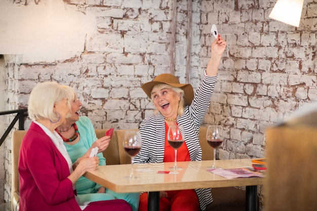 Foto kartenspielen. ältere gutaussehende fröhliche frauen, die karten spielen und genossen aussehen looking