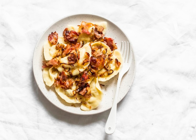 Kartoffel-Pierogi mit gebratenem Speck und Zwiebeln köstliches hausgemachtes Mittagessen auf hellem Hintergrund Draufsicht