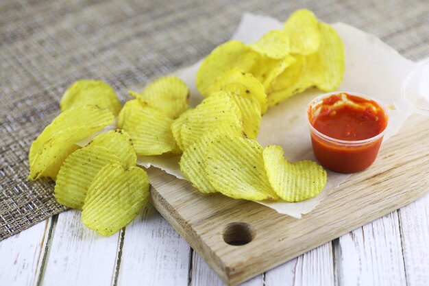 Kartoffelchips auf einem Holztablett auf einem weißen Tisch