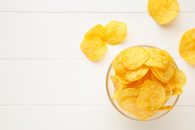 Kartoffelchips auf Schüssel auf weißer Holzwand