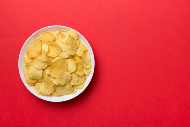 Kartoffelchips auf Schüssel isoliert auf farbigem Hintergrund Köstliche knusprige Kartoffelchips in Schüssel Platz für Text Ansicht von oben