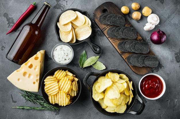 Kartoffelchips. Biersnacks, Sauce mit Käse und Zwiebeln, mit Dip-Saucen, auf grauem Steintisch, Draufsicht flach gelegt