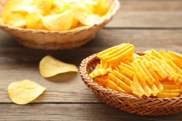 Kartoffelchips im Korb auf grauer Holzwand.