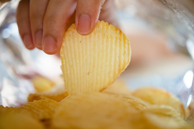 Kartoffelchips im Snackbeutel von Hand pflücken