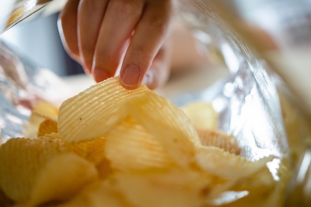 Kartoffelchips im Snackbeutel von Hand pflücken