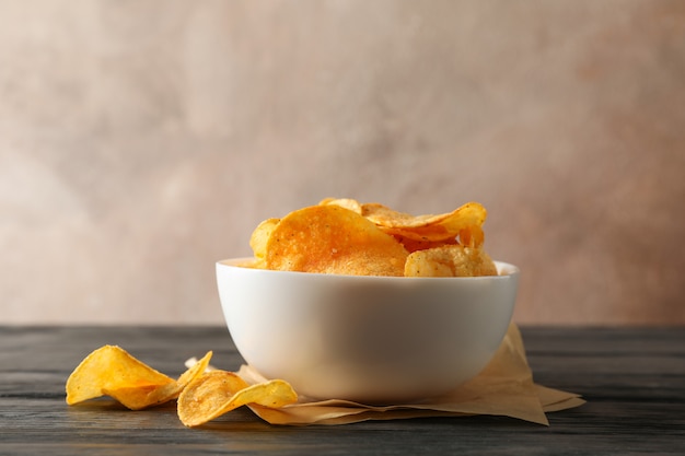 Kartoffelchips in einer Schüssel, Bastelpapier auf Holztisch auf Braun, Platz für Text