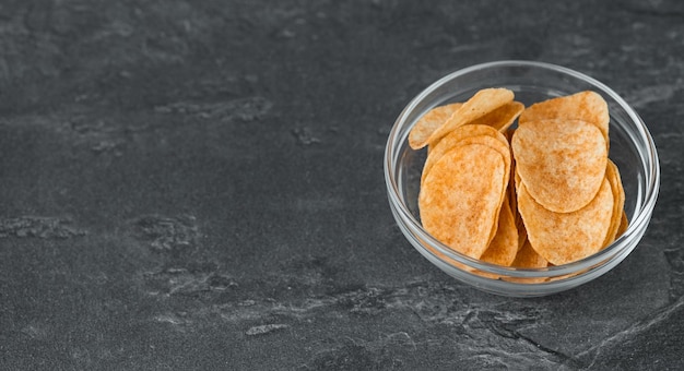 Kartoffelchips in Glasschale auf dunklem Hintergrund Fast Food