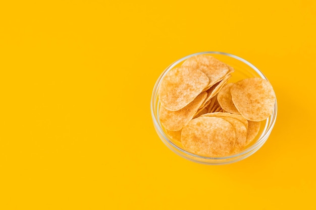 Kartoffelchips in Glasschale auf gelbem Hintergrund Fast Food