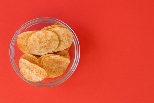 Kartoffelchips in Glasschale auf rotem Hintergrund Fast Food