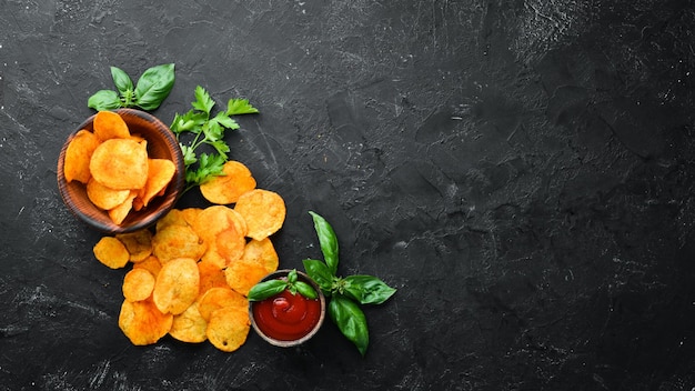 Kartoffelchips mit Gewürzen auf schwarzem Hintergrund Snacks zum Bier Ansicht von oben Freier Platz für Text