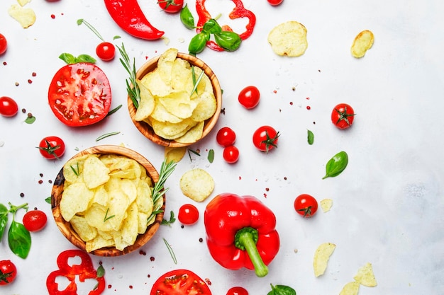 Kartoffelchips mit Salz und Rosmarin auf einem Hintergrund mit Tomaten-Chili- und Paprikagewürzen und Draufsicht des grünen Basilikums