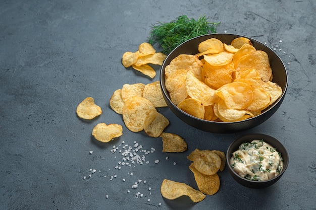 Kartoffelchips, Sauce, Dill auf grauem Hintergrund. Vorspeise für Bier.