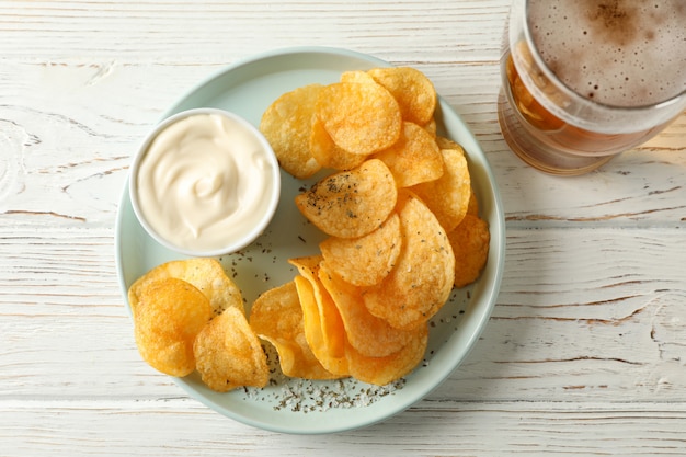 Kartoffelchips und ein Glas Bier. Bier Snacks, Sauce auf weißem Holz, Platz für Text. Draufsicht