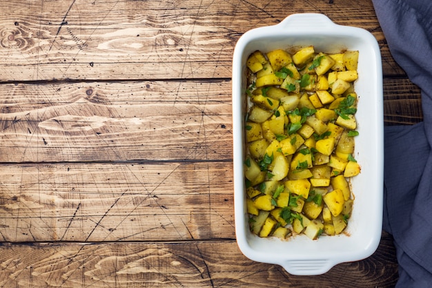 Kartoffeln gebacken mit Gewürzen und Kräutern in einem keramischen Backblech. Vegetarische Küche Platz kopieren