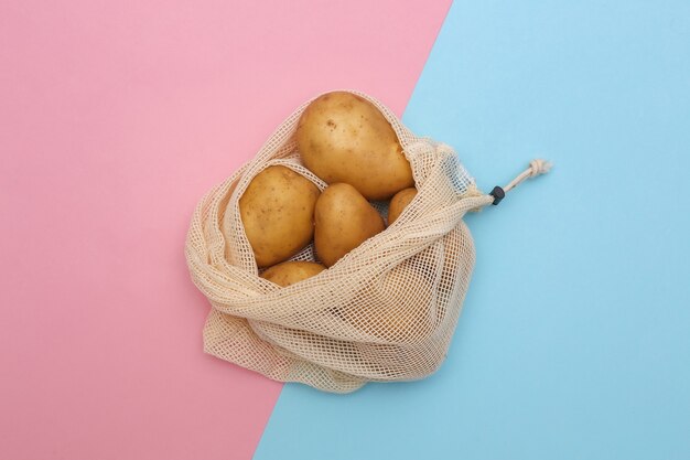 Kartoffeln im Öko-Baumwollbeutel auf rosa blauem Pastellhintergrund