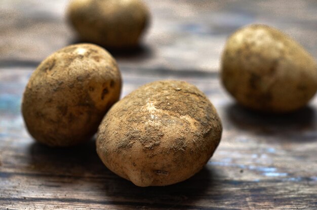 Kartoffeln liegen auf einem Holzbrett als Hintergrund und Nahaufnahmen von Speisen auf dem Tisch.