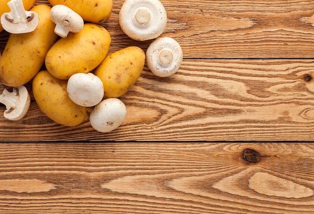 Kartoffeln und Pilze auf einem hölzernen Hintergrund