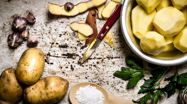 Kartoffelnahrung. Das Konzept der geschälten Kartoffeln in einer Schüssel auf dem rustikalen Tisch. Draufsicht