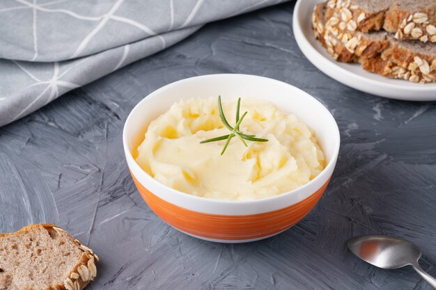 Kartoffelpüree in der Schüssel und Roggenbrot auf dem grauen Tisch gesundes Essen