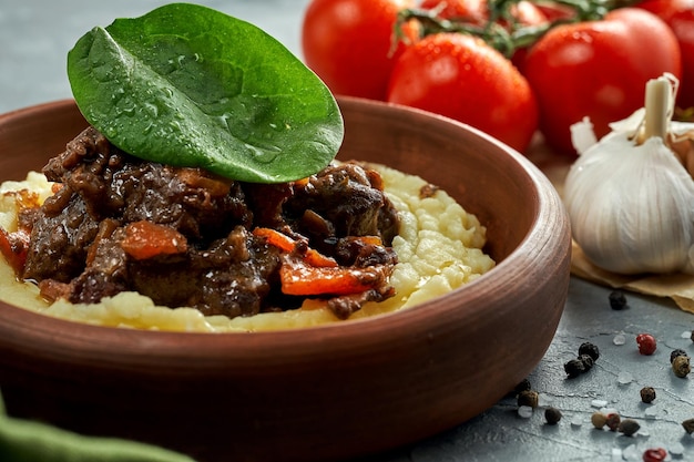 Kartoffelpüree mit gedünstetem Fleisch in einer Tonschale auf einem Betongrund