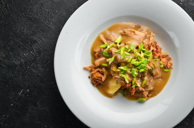 Kartoffelpüree mit Kalbssauce und Fleisch auf einem Teller. Ansicht von oben.