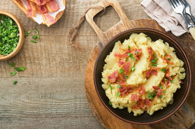 Kartoffelpüree Speck-Kartoffelpüree mit Frühlingszwiebelpfeffer und Cheddar-Käse in Schüssel auf alten hölzernen Hintergründen Köstliche cremige Kartoffelpüree Ansicht von oben