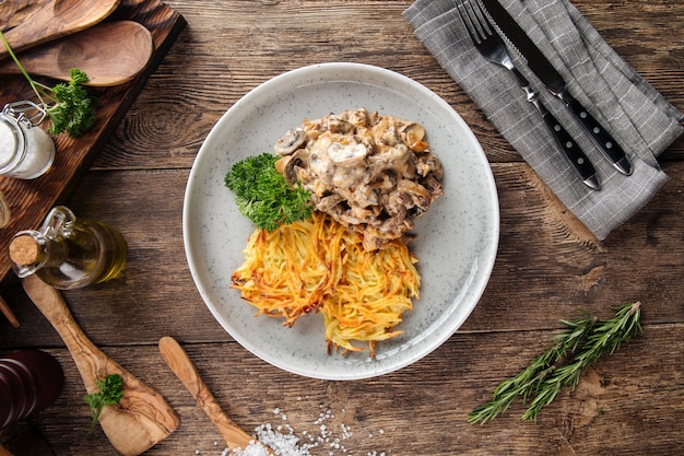 Kartoffelpuffer mit Stroganoff vom Rind auf grauem Teller