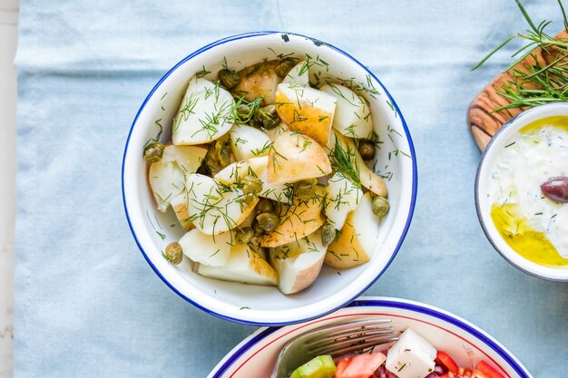 Kartoffelsalat mit Dill und Oliven in einer Schüssel auf blauem Hintergrund Gesundes Essen vegane und magere Rezepte