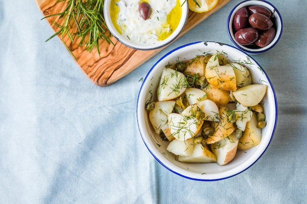 Kartoffelsalat mit Dill und Oliven in einer Schüssel auf blauem Hintergrund Gesundes Essen vegane und magere Rezepte