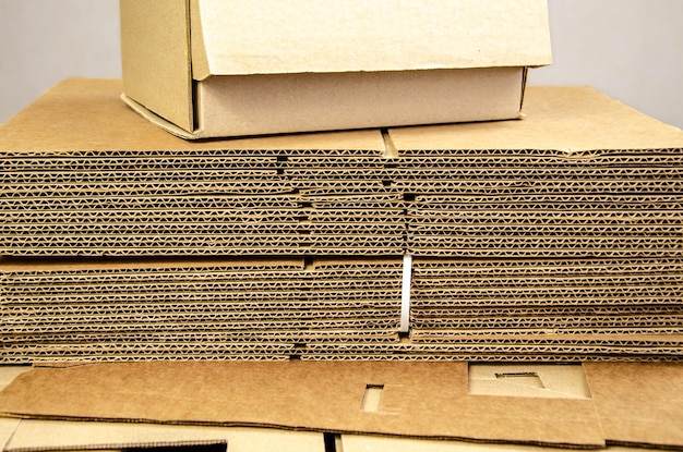 Karton bereit für die Produktverpackung und ein Stapel gefalteter Wellpappenblätter auf einem Tisch