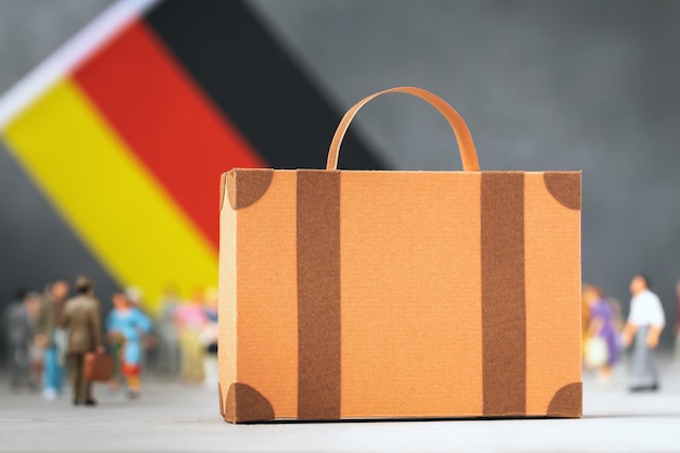 Kartonkoffer Plastikspielzeug Menschen Flaggenkonzept zum Thema Umzug oder Migration nach Deutschland