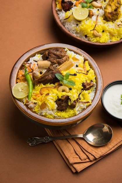 Kashmiri Mutton Gosht o Lamb Biryani preparado en arroz basmati servido con salsa de yogur sobre fondo cambiante, enfoque selectivo