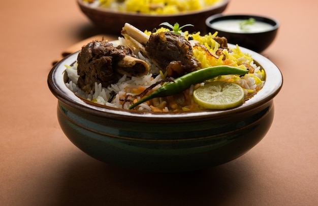 Kashmiri Mutton Gosht o Lamb Biryani preparado en arroz basmati servido con salsa de yogur sobre fondo cambiante, enfoque selectivo