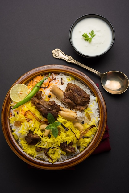 Kashmiri Mutton Gosht ou Lamb Biryani preparado em arroz Basmati servido com molho de iogurte sobre fundo temperamental, Foco seletivo