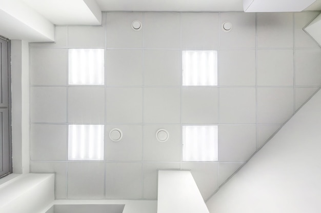 Kassettendecke mit quadratischen Halogenspots und Trockenbau in leerem Raum in Wohnung oder Haus Spanndecke weiß und komplexe Form Blick nach oben