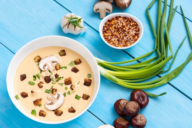 Kastaniensuppe auf einem Holztisch mit Zwiebeln und Knoblauch.