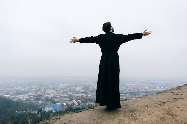 Katholischer bärtiger Priester, der draußen in den Bergen aufwirft