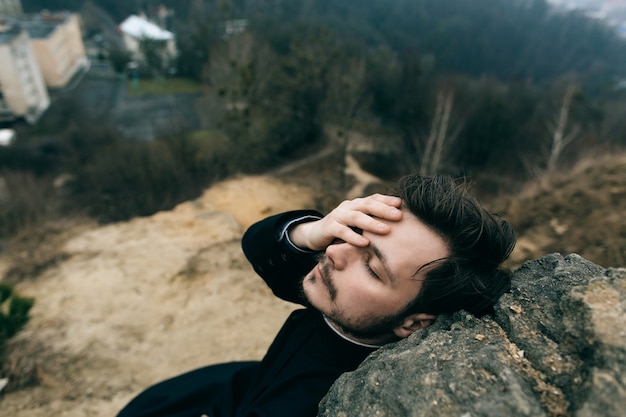 Katholischer bärtiger Priester, der draußen in den Bergen aufwirft