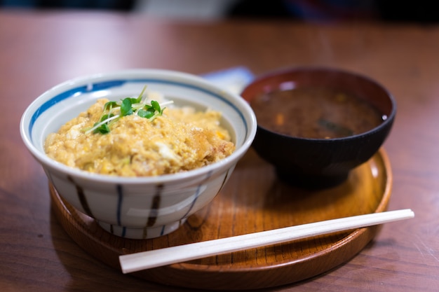 Katsudon serviert in einer großen japanischen Reisschüssel mit einem Paar Essstäbchen.