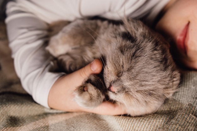 Katze und Junge, die zusammen schlafen, umarmten sich