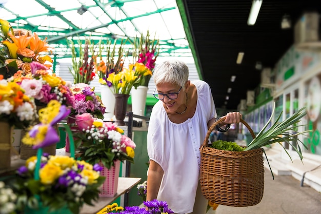 Kaufende Blumen der älteren Frau Charrming auf Markt