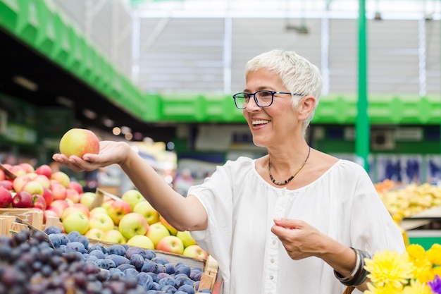 Kaufende Frucht der älteren Frau auf Markt