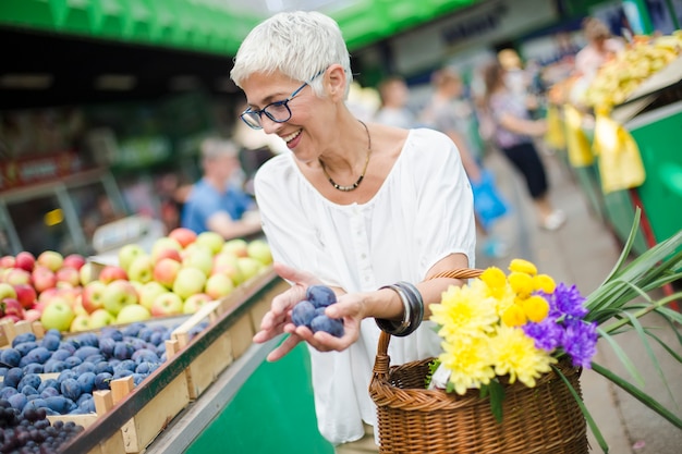 Kaufende Frucht der älteren Frau auf Markt